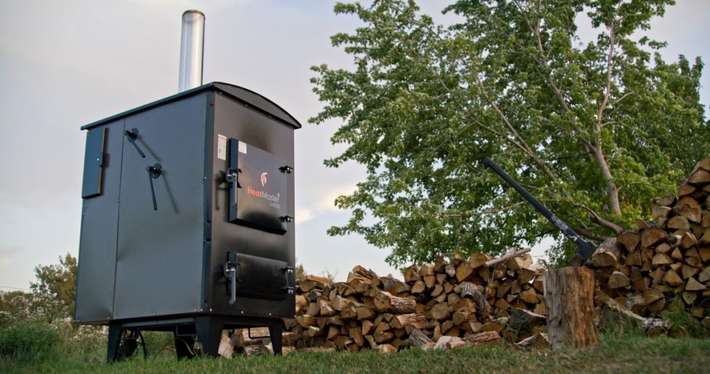 heatmasterss outdoor furnace next to some cut logs